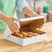 A woman opening a white Southern Champion Bakery Box filled with pastries.