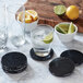 A set of Fox Run black marble coasters on a counter with glasses and limes.