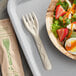 A bowl of salad with a World Centric compostable fiber fork on a table.