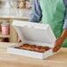 A woman holding a Southern Champion bakery box of donuts on a table.