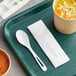 A green tray with a bowl of soup and a white World Centric compostable spoon with a napkin.