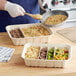 A person using a World Centric compostable fiber catering pan with dividers to serve rice and vegetables.