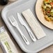 A tray with a white World Centric compostable fork and knife and a napkin.