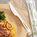A World Centric compostable TPLA knife on a wooden plate with a fork.