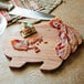 An Ironwood acacia wood pig-shaped serving board with bacon and a knife on it.