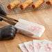 A person using tongs to place fried food in a Kari-Out Lady Design glassine bag.