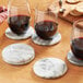 A group of Fox Run white marble coasters on a table with glasses of wine.