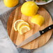 Lemon slices and wedges on an Ironwood acacia wood serving board next to a knife.