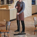 A man in an apron using a Vikan black single blade floor squeegee with a black handle in a restaurant.