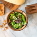 An Ironwood acacia wood bowl filled with salad with walnuts.