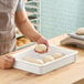 A person holding a ball of dough in a white fiberglass dough proofing box.