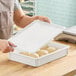 A person holding a MFG Tray white fiberglass dough proofing box lid with dough.