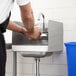 A man washing his hands in a Regency wall-mounted hand sink with side splash.