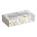 A Kleenex tissue box with gold foil on the front.