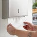 A person using Scott Professional white C-fold paper towels to refill a paper towel dispenser.