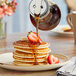 Mrs. Butterworth's Original Breakfast Syrup being poured onto a stack of pancakes.