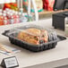 A plastic container with food inside a black Pactiv MealMaster chicken barn.