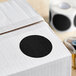 A white box with a roll of black semi-gloss paper labels with black circles on it.