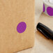 A brown box with a purple Lavex round label with a purple circle on it.
