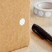 A roll of white Lavex round inventory labels with white circles on them.