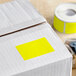 A box with a roll of bright yellow rectangular Lavex inventory labels.