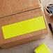 A cardboard box with a roll of Lavex fluorescent chartreuse rectangular inventory labels with a yellow label on it.