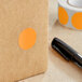 A roll of Lavex fluorescent orange paper circle stickers with a black pen.