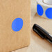 A roll of Lavex light blue round inventory labels with a black pen.