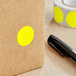 A roll of bright yellow Lavex round inventory labels with a black pen nearby.