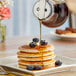 A stack of pancakes with Log Cabin syrup being poured over them.