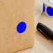 A brown box with a Dark Blue Lavex round label with a blue circle on it.