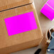 A cardboard box with a pink rectangular sticker on it.