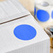 A white box with a roll of light blue round paper labels with a blue circle on it.