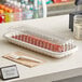 A Pactiv white plastic container with meat in it on a counter.