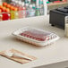 A Pactiv plastic container of food on a deli counter with a pair of plastic forks.