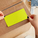 A person's hands applying a Lavex chartreuse rectangular label to a cardboard box.