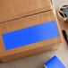 A cardboard box with a roll of Lavex light blue rectangular inventory labels with a blue semi-gloss paper label on the corner.