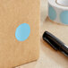 A brown box with a blue round sticker on it and a black pen.