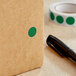 A black pen writing on a brown Lavex box with green dots.