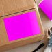 A cardboard box with a Lavex fluorescent pink rectangular label on it.