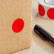 A red circle label on a brown surface next to a roll of tape.