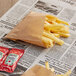 A newspaper with french fries in a Bagcraft EcoCraft natural paper bag.