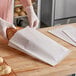 A person in gloves holding a Bagcraft Dubl Wax white bread bag.