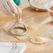 A hand using Imperia ravioli cutter to cut dough into circles.