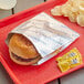 A hamburger in a Bagcraft printed foil wrapper.