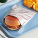 A Bagcraft printed foil hamburger bag with a burger and potato chips on a tray.