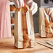 A hand in a glove putting a bagel in a Bagcraft natural C-Thru bakery bag with a window.