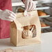 A person in a white apron putting a bag of cookies in a Bagcraft natural bakery bag with a Tac Seal.