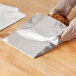 A person in gloves holding a sandwich in a Bagcraft foil sandwich bag.