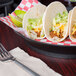 A plate of tacos served in HS Inc. round deli servers on a table.